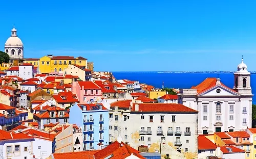 Bunte Dächer und Gebäude in Lissabon mit Blick auf das Meer.