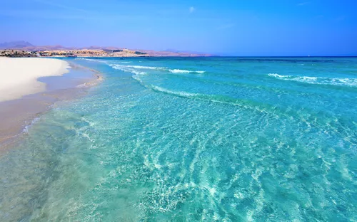 Strand von Costa Calma auf Fuerteventura mit weißem Sand und klarem blauem Ozeanwasser.