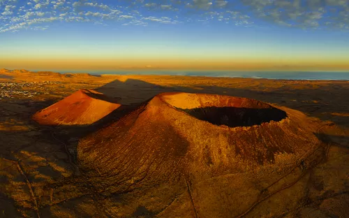 Vulkanische Kraterlandschaft in der Wüste bei Sonnenuntergang.