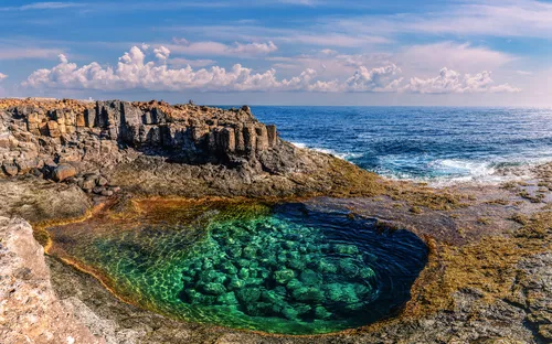 Natürliche Pools in Caleta de Fuste auf Fuerteventura mit klarem Wasser und Felsen im Hintergrund.