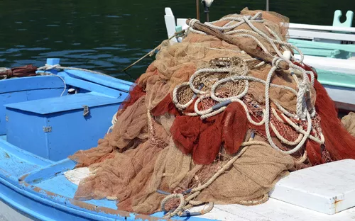 Ein blauer Fischerboot mit einem Haufen von Fischernetzen darauf.