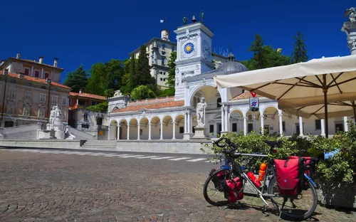 Fahrrad auf der Piazza Libertà in Udine, Italien, mit einem historischen Gebäude im Hintergrund.