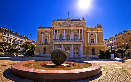 Historisches Gebäude mit Brunnen und Kugel in sonniger Umgebung.