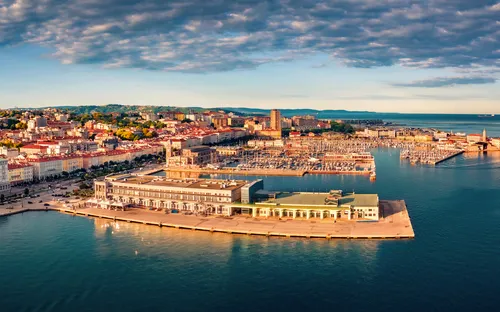 Küstenstadt mit Hafen und Gebäuden unter blauem Himmel.