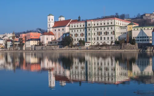 Historische Stadtansicht mit Flussreflexionen bei klarem Himmel.