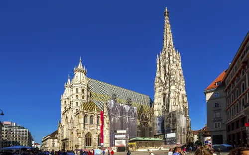 Stephansdom in Wien bei klarem blauem Himmel, Menschenmenge im Vordergrund.