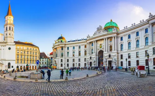 Historisches Gebäude und Kirche mit gepflastertem Platz und Menschen.