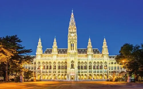 Das Wiener Rathaus bei Nacht, hell erleuchtet vor klarem, dunkelblauem Himmel.