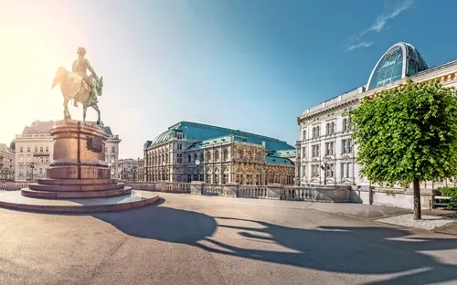 Reiterstatue auf großem Platz vor historischen Gebäuden bei Sonnenschein.
