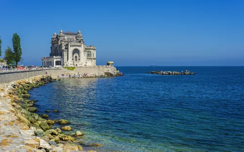 Historisches Gebäude an Küste mit blauem Meer und klarem Himmel.