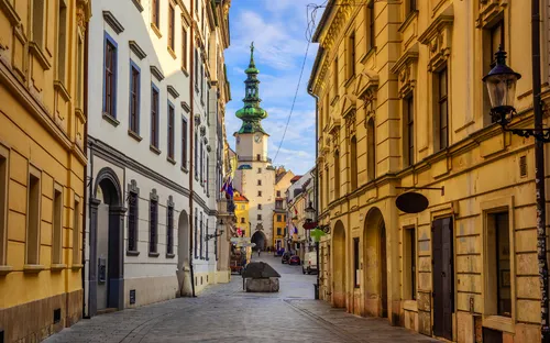 Leere Straße in Altstadt mit historischer Architektur und Turm im Hintergrund