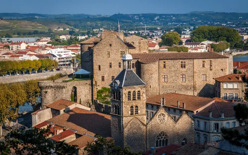 Historische Burg und Kirche in einer französischen Stadtlandschaft im Sonnenschein.