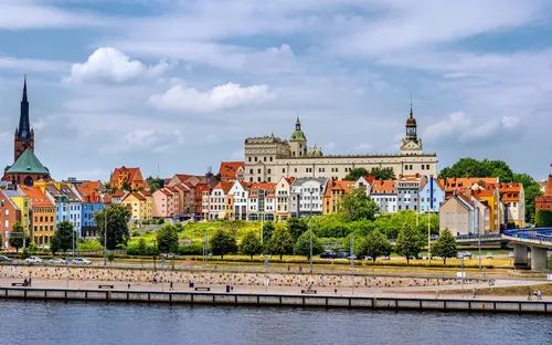Stadtansicht mit historischen Gebäuden und Fluss im Vordergrund.