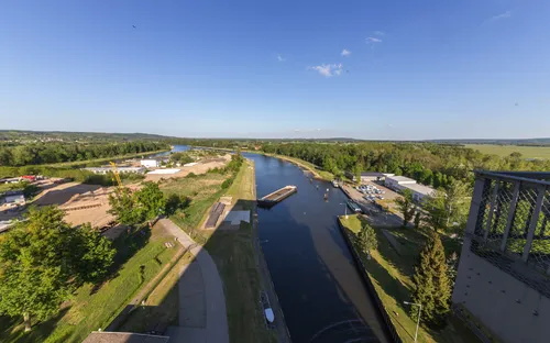 Kanal mit Schleuse und Umgebung aus der Vogelperspektive bei sonnigem Wetter.