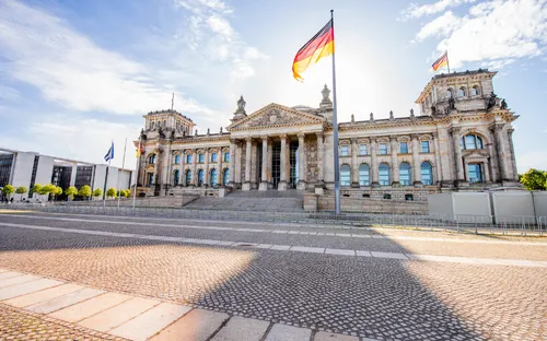 Das Reichstagsgebäude in Berlin mit wehender deutscher Flagge.