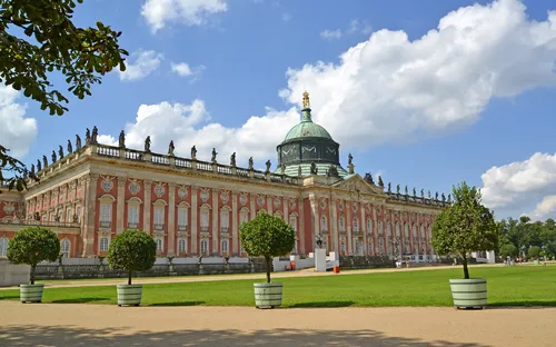 Barockes Gebäude mit Kuppel und Statuen, umgeben von Gartenanlagen.