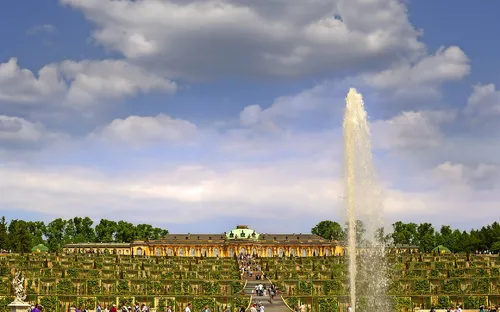 Schloss Sanssouci mit Park und Fontäne unter blauem Himmel