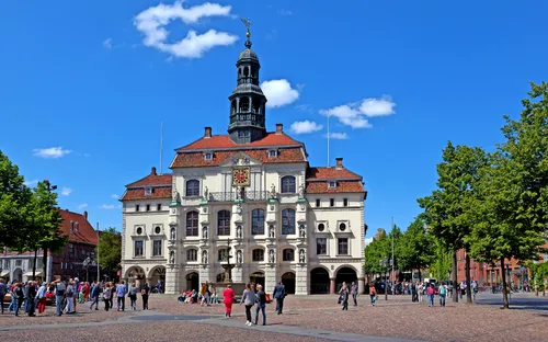 Historisches Rathaus auf einem Platz mit Menschen bei sonnigem Wetter.