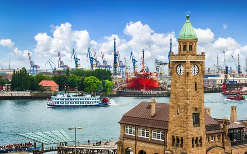 Hafenansicht mit Turm und Schiff vor blauem Himmel im Hintergrund.
