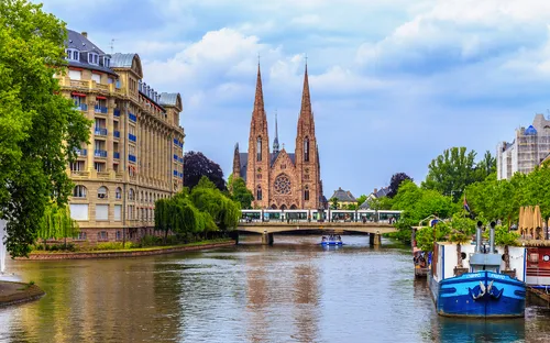 Fluss mit Kirche und Häusern im Hintergrund, Brücke über dem Wasser.