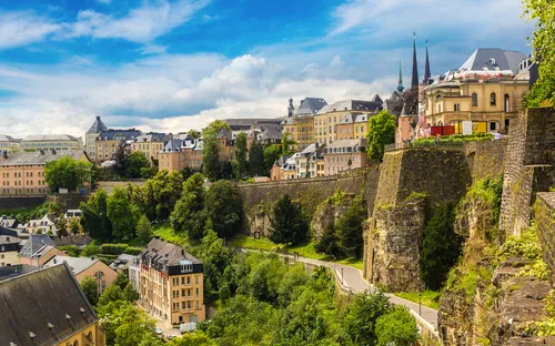 Stadtansicht von Luxemburg mit alten Gebäuden und bewaldeten Hängen.
