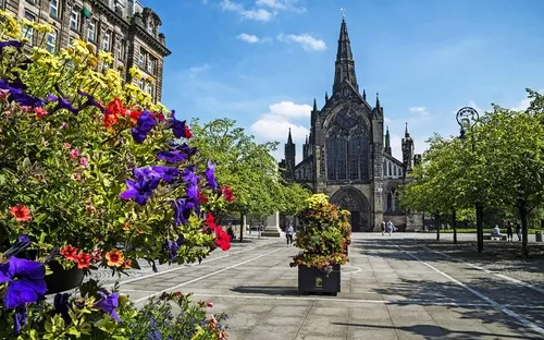 Historische Kirche mit bunten Blumen und Bäumen im Vordergrund.