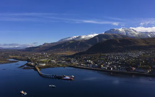 Luftaufnahme eines Hafens mit Bergen im Hintergrund.