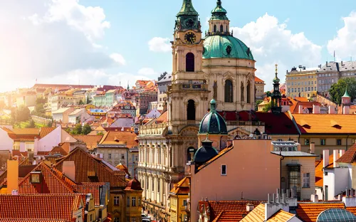 Ansicht von Prag mit Sankt-Nikolaus-Kirche und bunten Gebäuden bei sonnigem Wetter.