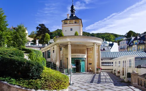 Eingangsbereich eines historischen Gebäudes mit Turm und Gartenansicht.