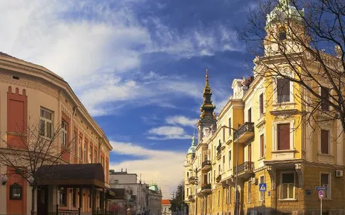 Eine leere städtische Straße mit historischen Gebäuden unter blauem Himmel.