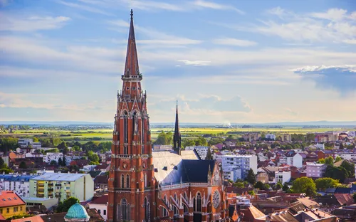 Historisches Gebäude mit Turm in städtischer Landschaft bei blauem Himmel.