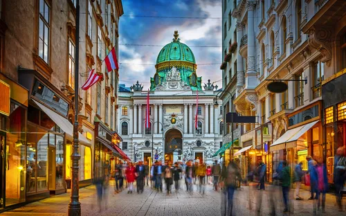 Menschen vor der Hofburg in Wien mit Kuppel und österreichischen Flaggen.
