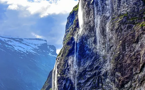 Wasserfälle Sieben Schwestern im Geirangerfjord, Norwegen, mit felsigen Klippen und grünem Wasser.